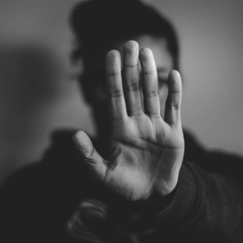 Verteidigung bei Mord, Raub, Erpressung Schwarz-weiße Aufnahme einer erhobenen Hand vor Gesicht - symbolisiert entschlossenen Schutz im Strafrecht